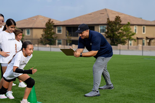 Champions Volleyball coach timing a youth athlete during an outdoor training drill